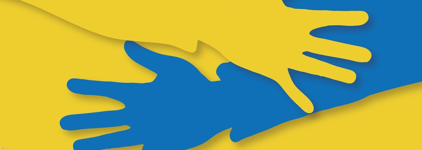 Sich umarmende Hände in den Farben der ukrainischen Flagge