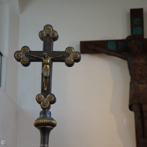 Altes Vortragekreuz mit dem Körper des Gekreuzigten, Im Hintergrund: großes Kruzifix über dem Altar